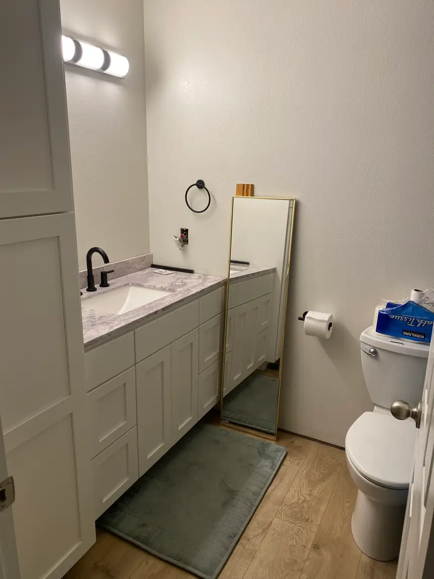 After: the same bathroom finished with a white vanity, stone counter, and new flooring
