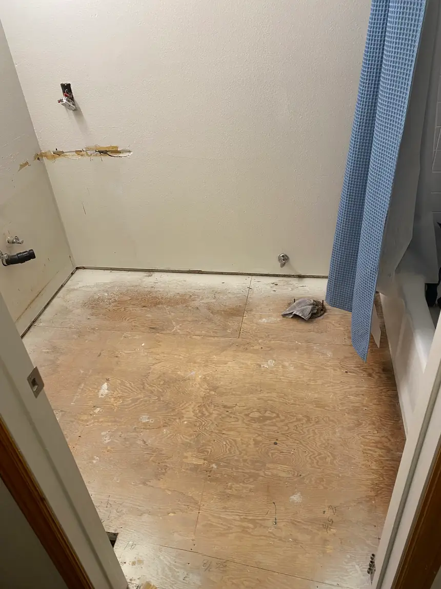 Before: a stripped-out bathroom with bare subfloor and open walls