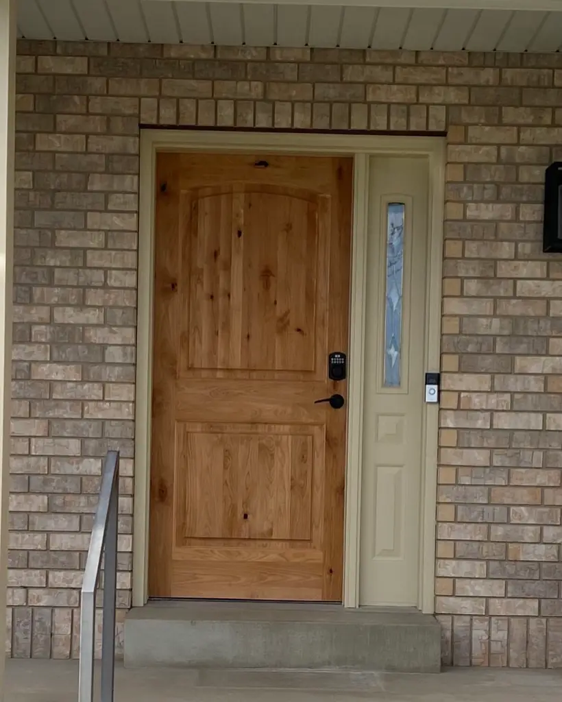 After: knotty alder front door and sidelight on the same brick home