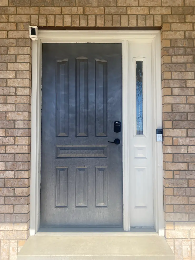 Before: painted blue-gray front door and sidelight on a brick home