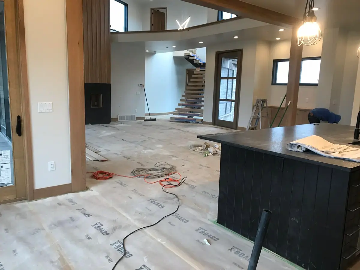 Before: a Park City great room under construction with floor protection, cords, and debris